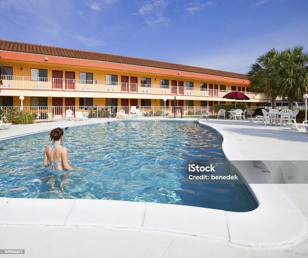 Hotel Swimming Pool Young woman standing in hotel swimming pool Motel Stock Photo