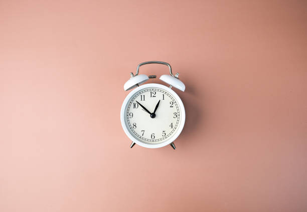 the white clock on an orange paste background represents time, management, deal, and planning. - clock time alarm clock orange imagens e fotografias de stock