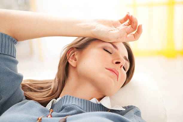 Tierd woman. Tiered woman lying down and holding hand on her forehead. Eyes closed. tierd stock pictures, royalty-free photos & images