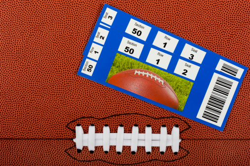 American Football Background with Tickets. A pair of t9ickets stubs sitting on a flat football with seam and white laces for a background
