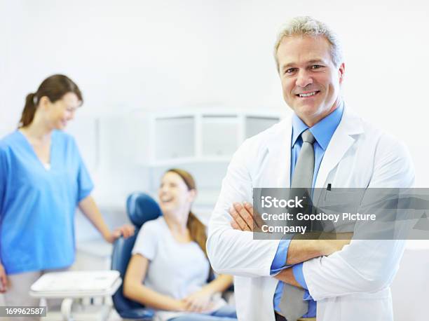 Foto de Dentista Com Paciente E Equipe No Plano De Fundo e mais fotos de stock de Sorrindo - Sorrindo, Equipamento dentário, Mulheres