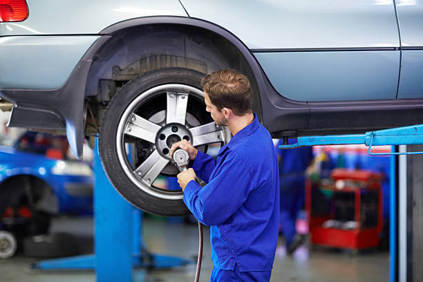 Securing the wheel A mechanic torquing the lug nuts of a wheel with a drill car mechanic top view stock pictures, royalty-free photos & images