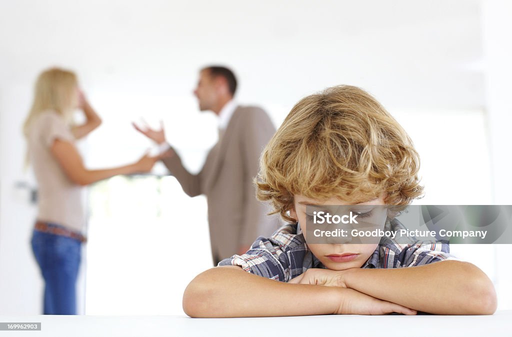 Unhappy with their arguments A sad young boy with his parents fighting in the background Child Stock Photo