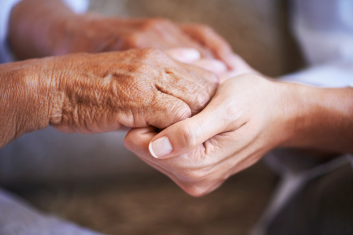 Close up of a young caucasian woman's hands holding a senior ethnic woman's hands