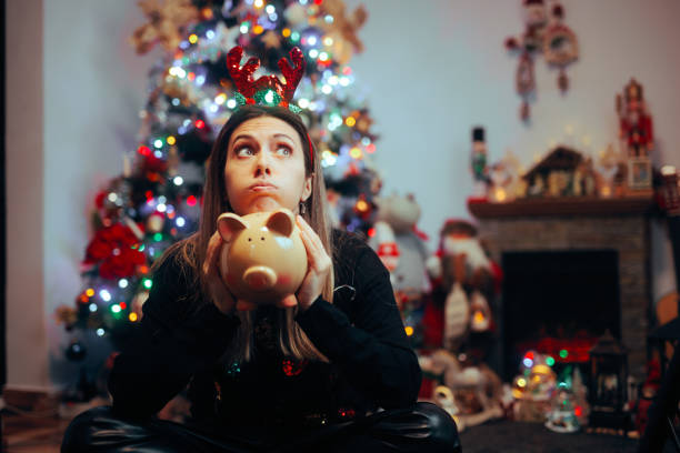 크리스마스 지출을 후회하는 돼지 저금통을 들고 있는 파산한 여자 - christmas emotional stress shopping holiday 뉴스 사진 이미지