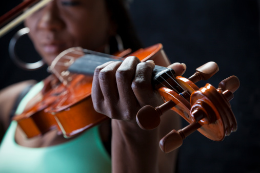 Ethnic minority woman playing violin on black background