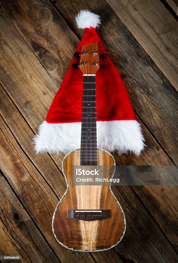 Christmas Uke A ukulele with a Christmas hat against a wooden background. Christmas Stock Photo