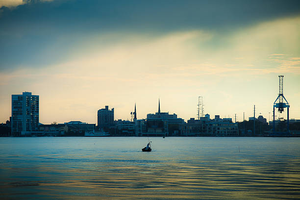 A silhouetted fisherman catches fish with the Charleston, South Carolina waterfront behind him.