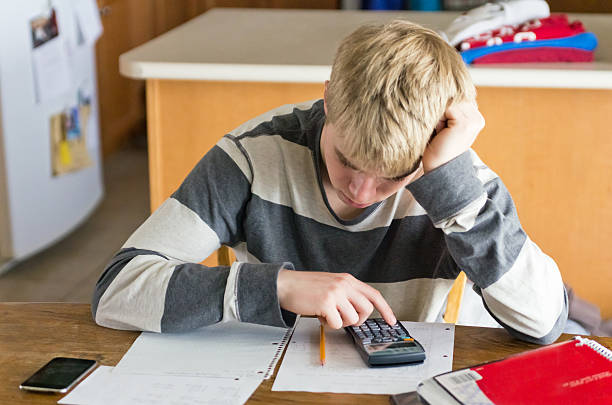 Teen Male Doing Homework at Kitchen Table stock photo