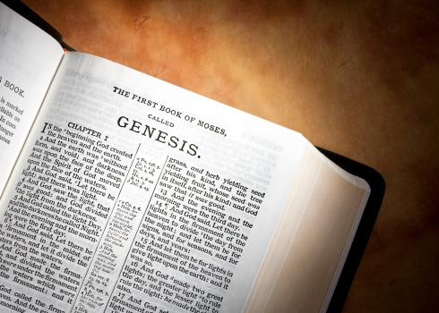 A new Bible (KJV) open to the first book, Genesis, with a parchment paper background.