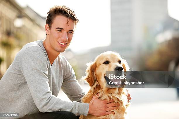 Lächelnd Teenager Und Seinen Hund Gut Behandelt Stockfoto und mehr Bilder von Männer - Männer, Porträt, Golden Retriever