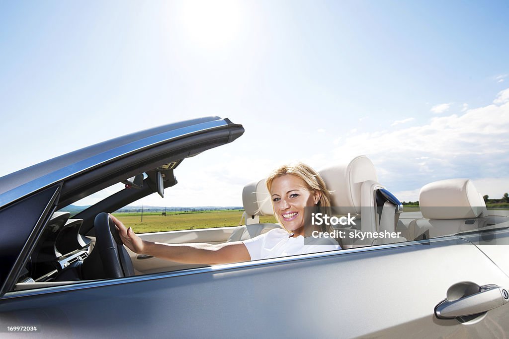 Sonriente Joven mujer conducir un vehículo - Foto de stock de Coche deportivo libre de derechos