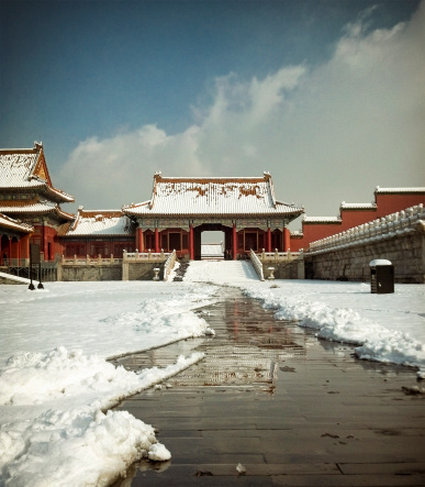Early morning in the Forbidden City in central Beijing, with a reflection seen in a path cleared through fresh snow.