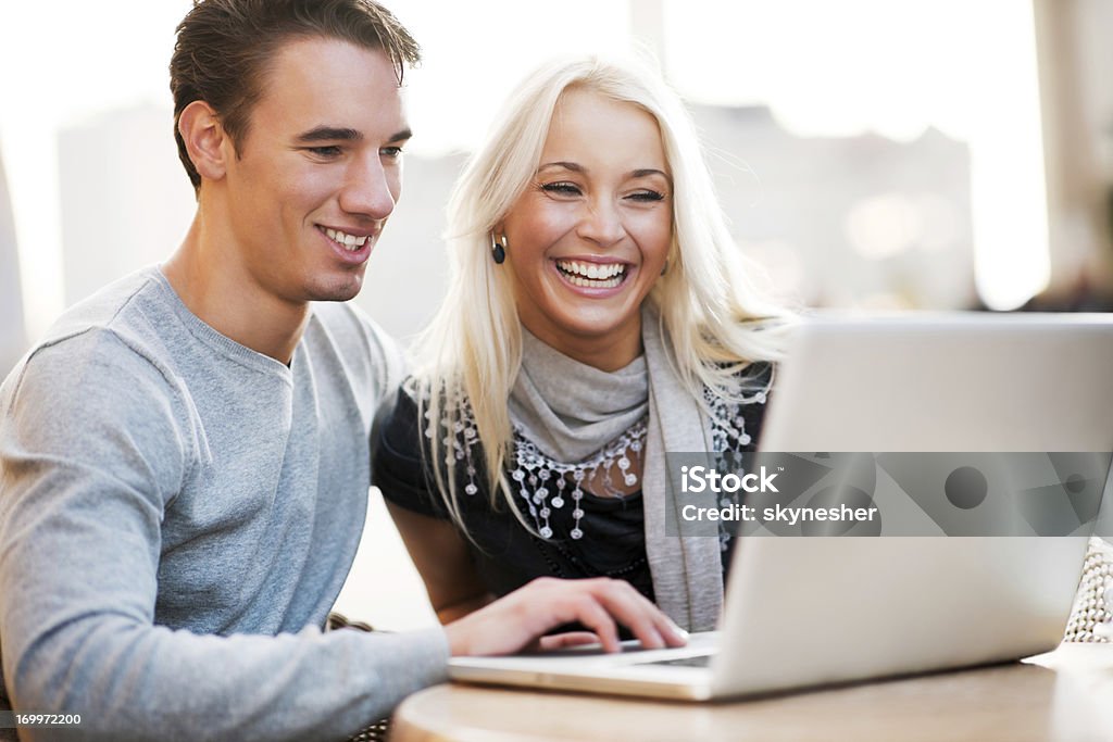 Hermosa pareja sentada en un café y el uso de una computadora portátil - Foto de stock de Aire libre libre de derechos