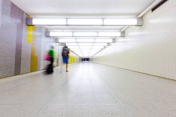 Two travelers with suitcases in tow walk down a long tile corridor at Los Angeles International Airport