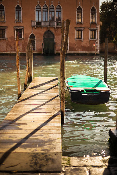 A small boat is moored to a dock on a canal in Venice, ItalyThe marble and plaster entrance hall of a centuries-old Venetian building
