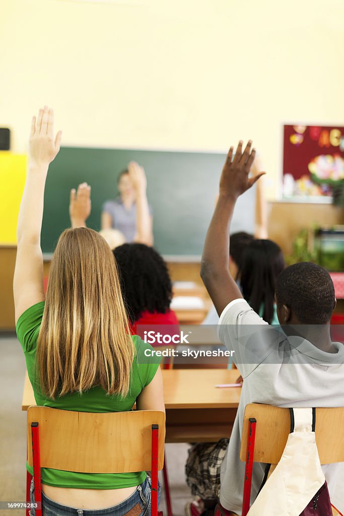 Grupo de Adolescentes sentados na sala de aula com as mãos levantadas - Royalty-free Vista Traseira Foto de stock