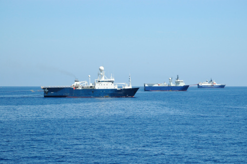 Three seismic survey ships pulling survey equipment. Seismic survey ships map the subsea geology using the seismic sound produced by air guns towed behind the vessel. The information is is used to locate oil and gas deposits.