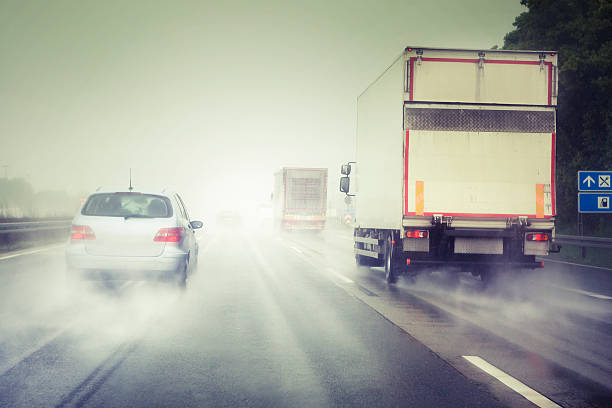 Bad weather on the highway Bad weather on the highway - overtaking car and trucks. Water on the windshield, dangerous situation. All recognisable logos and number plates have been carefully removed, backside of the car has been modified in order to create a generic look. Photography has been taken during driving - some minor motion blur. Cross processed image truck rain stock pictures, royalty-free photos & images