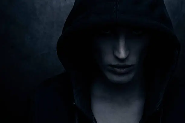 Hooded person on dark background