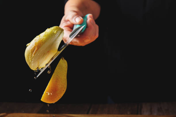 woman cutting a pear in half with a knife in the air