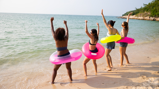 Dance. Group of teenager girls dancing on ther beach. Four teenager girl female enjoying on inflatable ring and dance on tropical beach. Vacation trip summer holiday. Gen Z