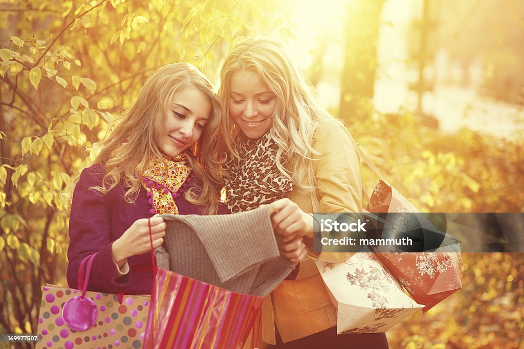 Gli amici dopo gli acquisti in autunno parco - Foto stock royalty-free di 20-24 anni