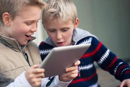 Boys playing happily on a tablet computer.