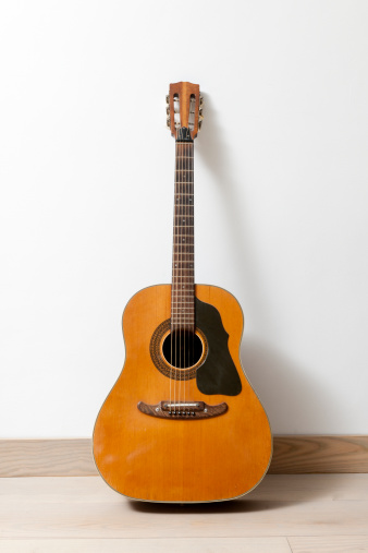 acoustic guitar standing on the floor in living room against white wall