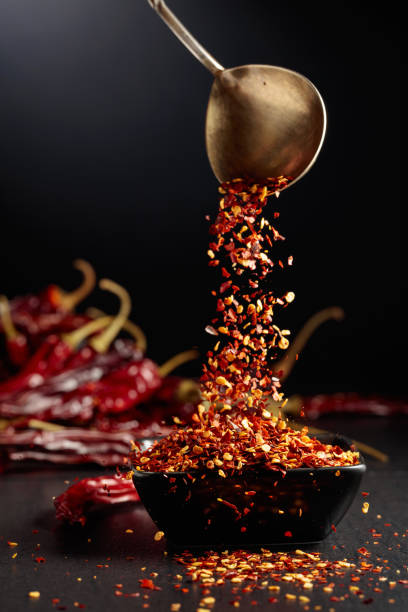 istock Chilli flakes are poured into a black dish. 1699785156
