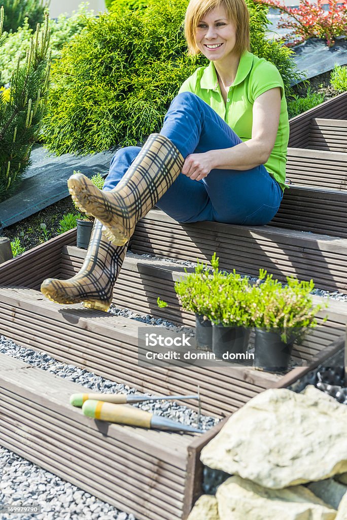 Mulher colocando em borracha botas, a partir de trabalho jardim, mudas de plantio - Foto de stock de Mulheres royalty-free