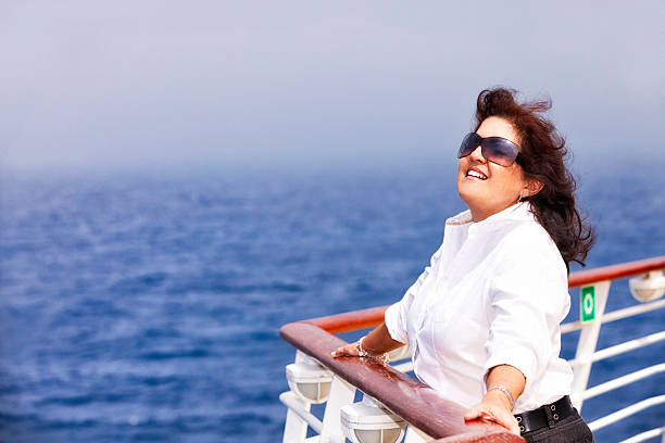 Happy relaxed woman enjoying on a cruise ship main deck ans breathing fresh ocean air.