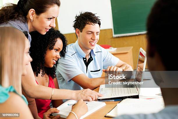 Side View Of Teacher Helping Students Use Computer Stock Photo - Download Image Now