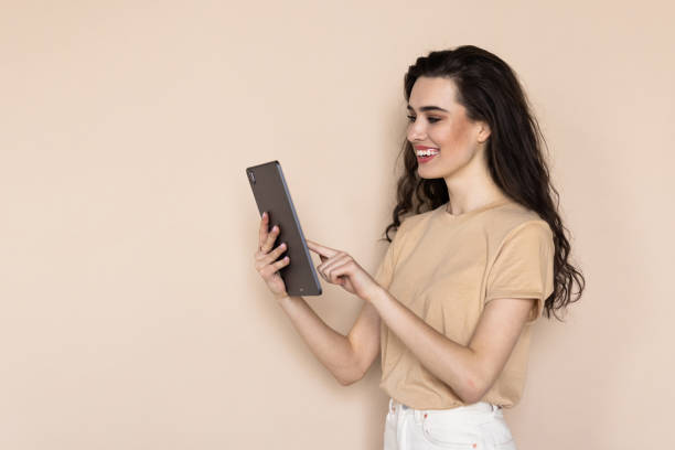 istock A young woman with a tablet in her hands on a beige background. 1699804759