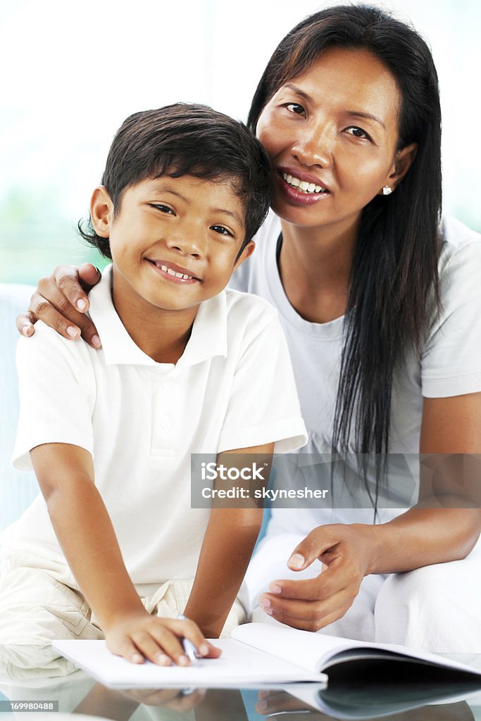 Asiatiche madre aiutando Suo figlio con i suoi compiti a casa. - Foto stock royalty-free di 30-34 anni