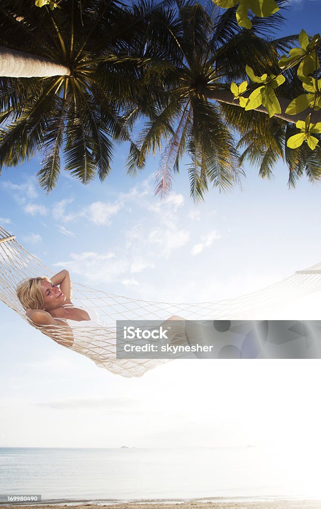 Giovane donna rilassante su un'amaca sulla spiaggia tropicale. - Foto stock royalty-free di Rilassamento