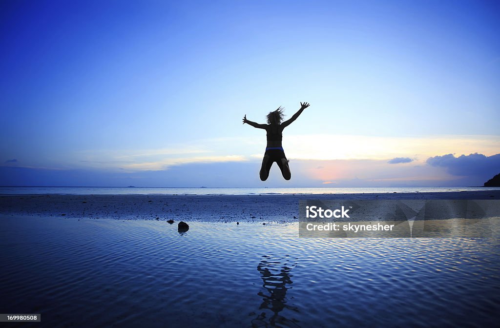 Silueta de mujer salto alto en el aire en la playa. - Foto de stock de Mujeres libre de derechos