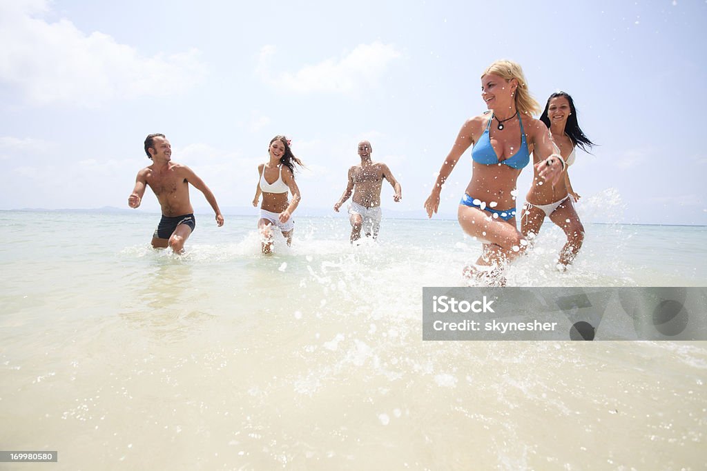 Gran grupo de jóvenes corriendo en el agua. - Foto de stock de Adulto joven libre de derechos