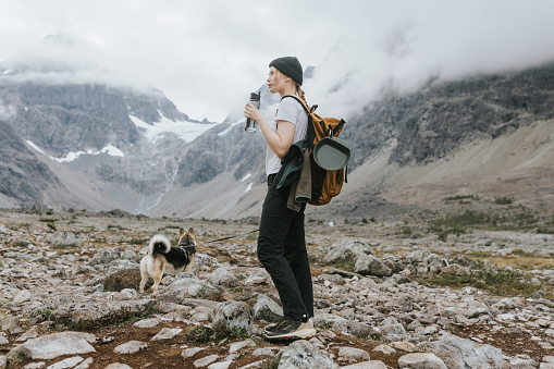 A young woman, filled with a sense of adventure, shares a beautiful moment with her dog while hiking through the captivating landscape of Norway.