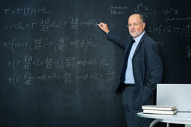 Science teacher writting at blackboard physics equation stock photo