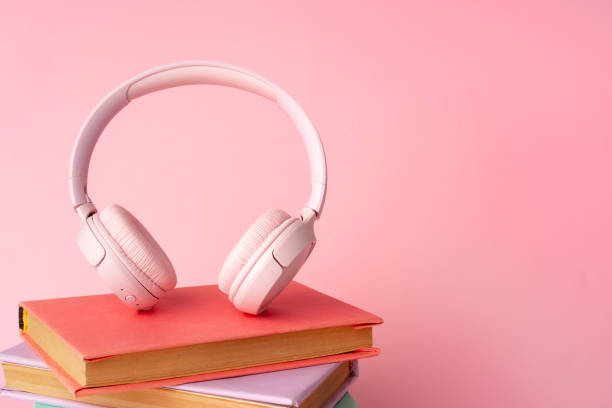 istock Pink headphones on a book on blue background 1699835859