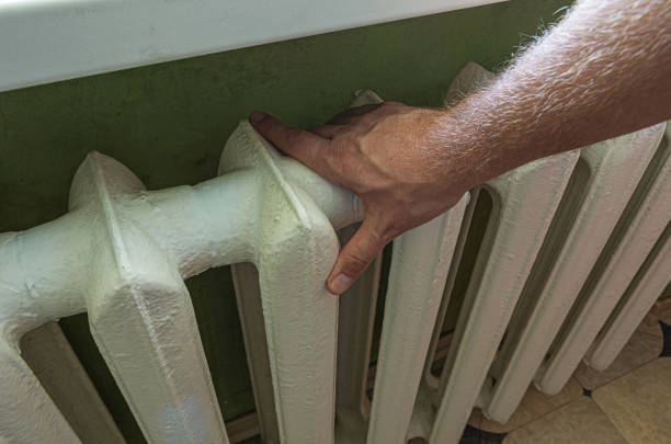 istock Male hand touching cast iron home radiator for checking temperature. 1699844932