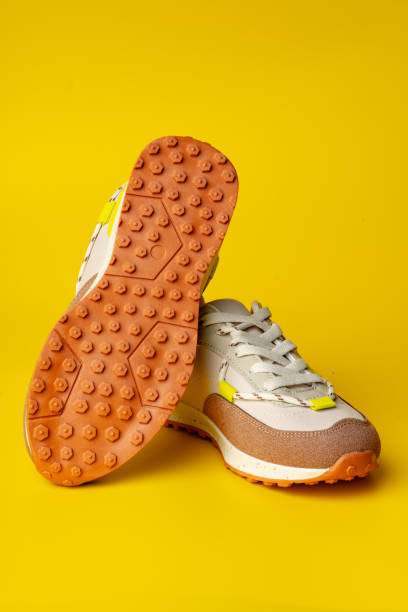 istock Beige sport running shoes on yellow studio background 1699847152
