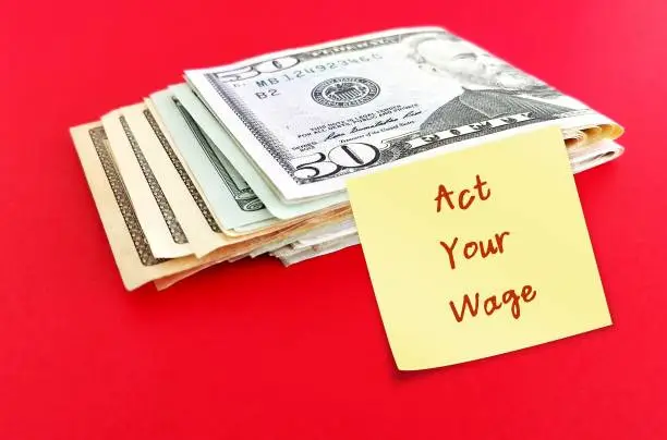 Cash money on red background with stick note written ACT YOUR WAGE, Cash money on red background with stick note written ACT YOUR WAGE, viral  workplace trend which employees respectfully decline tasks that  not paid or financially compensated for