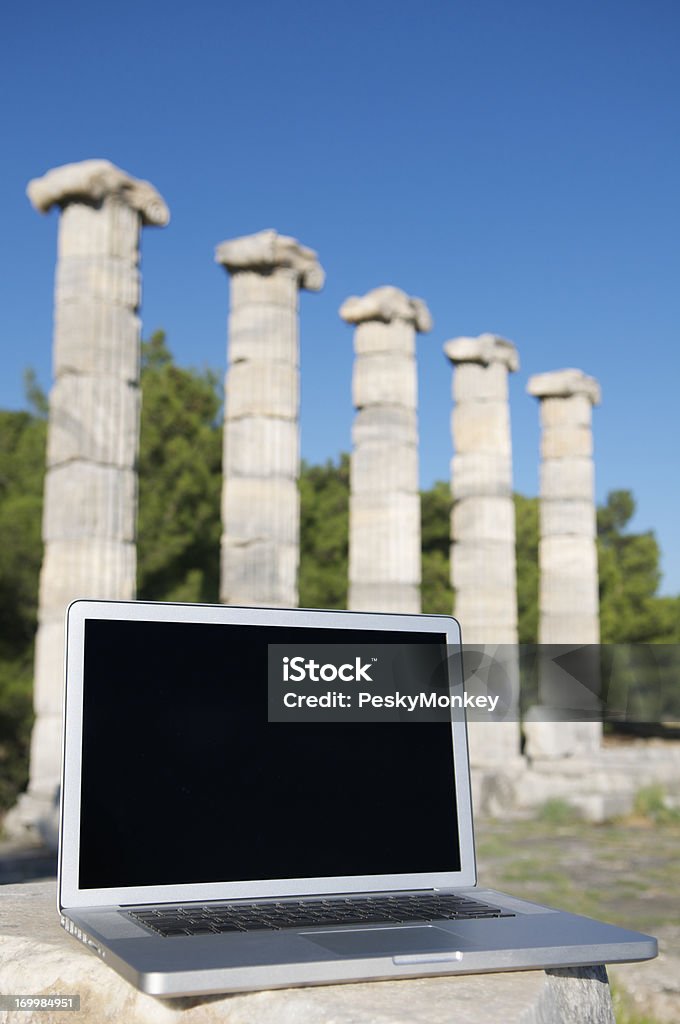 Ordenador portátil blanco s'encuentra antes de fila de la antigua columnas - Foto de stock de Grecia - Europa del sur libre de derechos