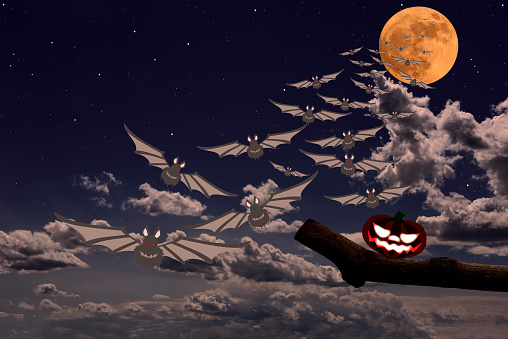 Strawberry supermoon rising over the Jack O' Lantern and flying bats in midnight.