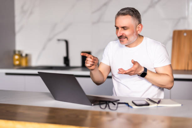 istock Confident middle aged man using laptop and having video call while working from home. 1699876170