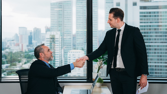 Businesspeople shaking hands in working space. Successful Businessmen Shaking Hands in a Modern Office.