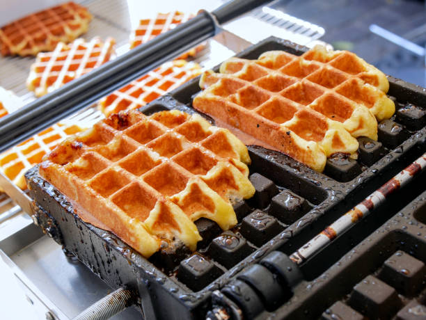 istock Two Liege waffles baking on their mold. 1699895078