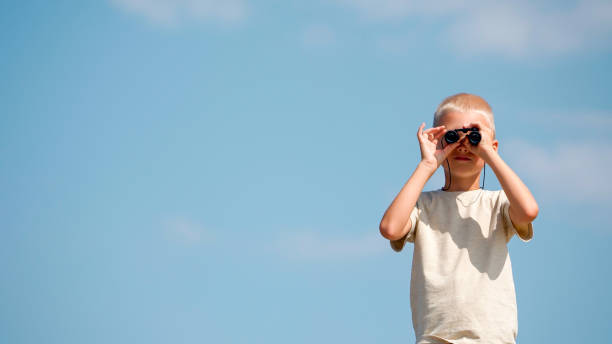 istock Portrait of a schoolboy looking through binoculars directly into the camera 1699895606